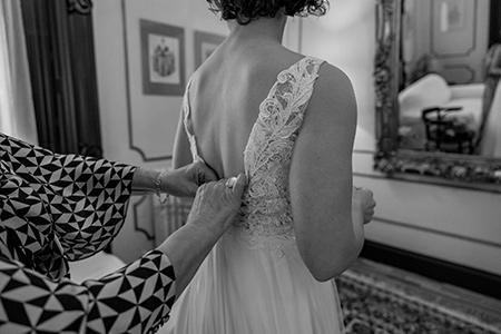 Preparativos de la novia mientras le ajustan el vestido antes de la boda