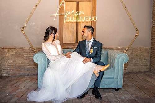 Pareja de novios sentados en sofá con letrero luminoso en su boda en Tudela