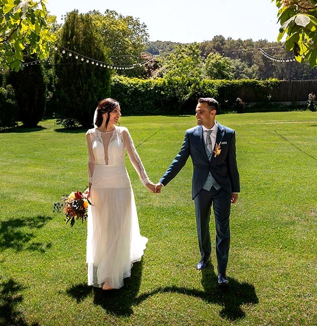 Pareja caminando de la mano por un jardín durante su boda en Barcelona
